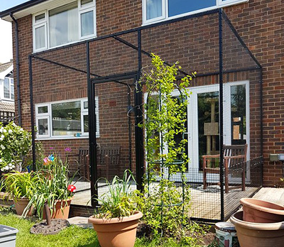 A black metal catio enclosure attached to a house