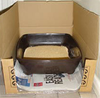 Cat litter tray inside a large cardboard box with one side removed.